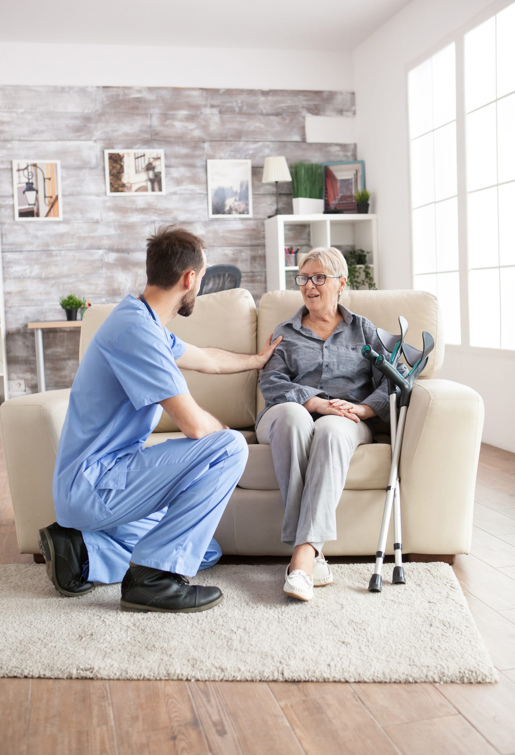 Male health visitor in a nursing home A caregiver woman doing cleaning tasks